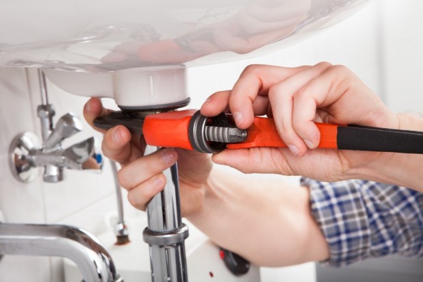Portrait of male plumber fixing a sink in bathroom